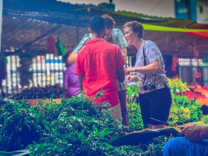 A guided Pettah Market tour with a local guide explaining to a couple, surrounded by vendors and market stalls